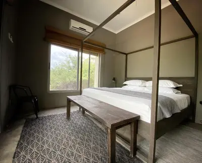 a bedroom with a bed and a wooden table at Nextdoor Kruger in Marloth Park