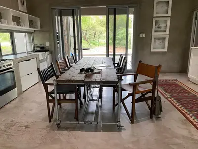 a dining room with a wooden table and chairs at Nextdoor Kruger in Marloth Park