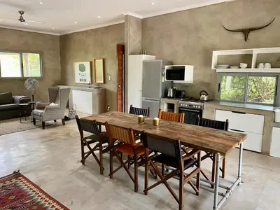 a kitchen and dining room with a wooden table and chairs at Nextdoor Kruger in Marloth Park