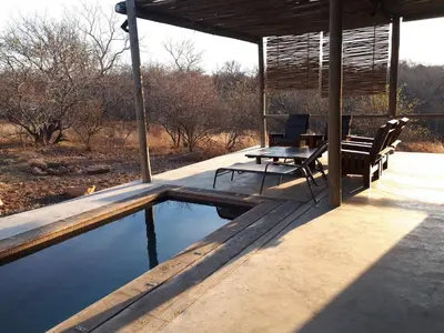 a patio with a table and chairs next to a pool at Nextdoor Kruger in Marloth Park
