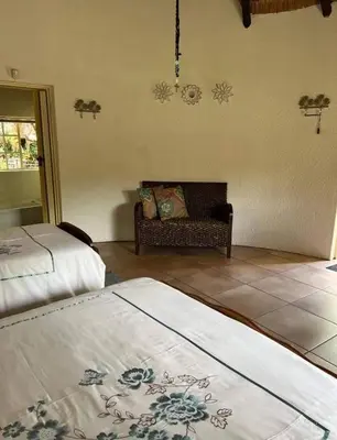 a living room with two beds and a couch at Bosveldsig Cottages in Modimolle