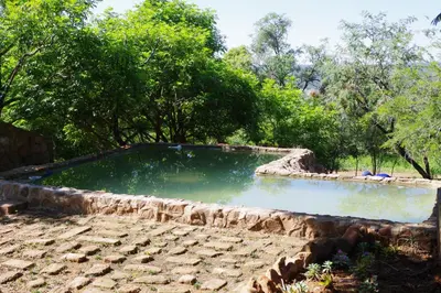 a pool of water with trees in the background at Bosveldsig Cottages in Modimolle