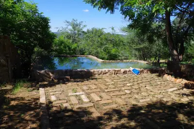 a stone patio with a pool of water in a yard at Bosveldsig Cottages in Modimolle