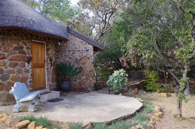 a stone house with a bench and a door at Bosveldsig Cottages in Modimolle