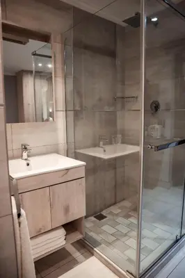 a bathroom with a glass shower and a sink at Cascades Guest Lodge in Nelspruit