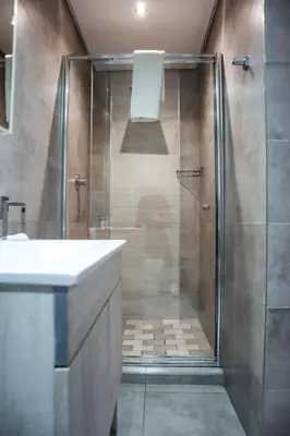 a bathroom with a shower with a sink and a glass shower stall at Cascades Guest Lodge in Nelspruit