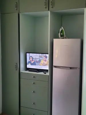 a tv sitting on a dresser next to a refrigerator at Arum Lily Guest Rooms in Pretoria