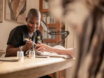 a man sitting at a table cutting a persons nails at Monkey Thorn Lodge & Wellness Spa - Adults Only in White River