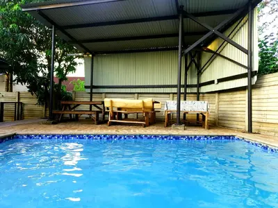a swimming pool with a pergola and a table and bench at SnL 38 Hoep Hoep in Malelane