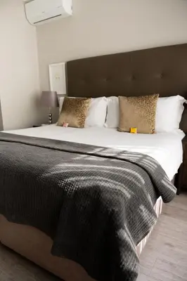 a large bed with a black blanket and pillows at Kyalami Creek in Midrand