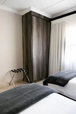 a bedroom with a bed and a wooden wall at Kyalami Creek in Midrand