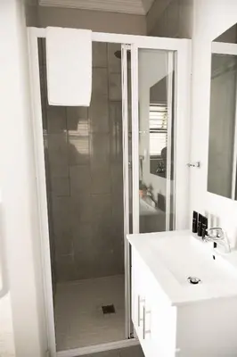 a bathroom with a shower and a white sink at Kyalami Creek in Midrand