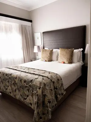 a bedroom with a large bed with white sheets and pillows at Kyalami Creek in Midrand