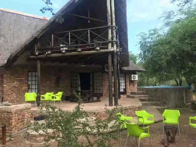 a building with green chairs in front of it at Mopani Manor in Marloth Park