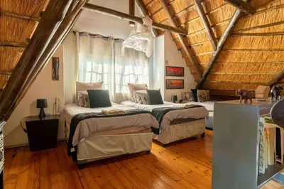 a bedroom with two beds and a wooden ceiling at Mopani Manor in Marloth Park