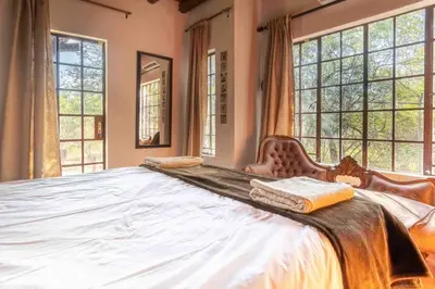 a large bed in a room with large windows at Mopani Manor in Marloth Park