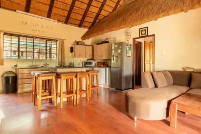 a living room with a couch and a kitchen at Mopani Manor in Marloth Park