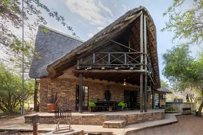 a brick house with a gambrel roof with a picnic table at Mopani Manor in Marloth Park