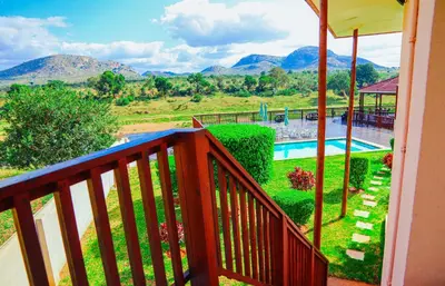 a balcony with a view of a pool and mountains at Riverview Inn in Malelane