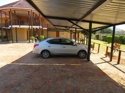 a small white car parked under a covered parking lot at Riverview Inn in Malelane