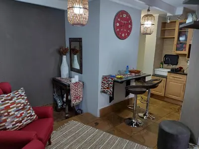 a living room with a red couch and a kitchen at Le Chateau Guest House and Conference Centre in Kempton Park