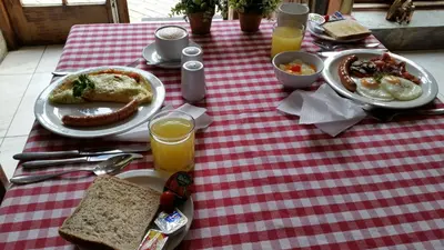 a red and white checkered table with breakfast food on it at Le Chateau Guest House and Conference Centre in Kempton Park