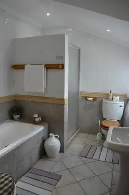 a bathroom with a tub and a toilet and a sink at Le Chateau Guest House and Conference Centre in Kempton Park