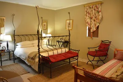 a bedroom with a bed and two red chairs at Le Chateau Guest House and Conference Centre in Kempton Park