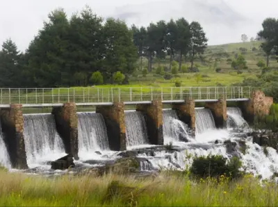 a bridge over a waterfall in a field at Marks Cottage in Dullstroom