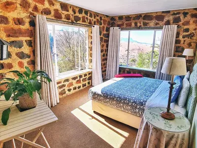 a bedroom with a bed and two large windows at Marks Cottage in Dullstroom