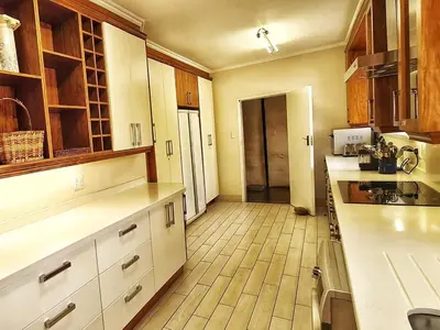 a kitchen with white cabinets and a wooden floor at Marks Cottage in Dullstroom
