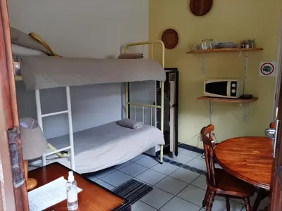 a small room with a bunk bed and a table at Elephant Walk Guesthouse and Back Packers in Phalaborwa