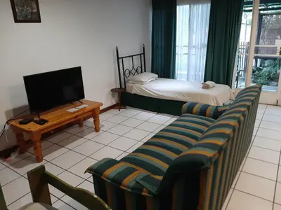 a living room with a couch and a tv and a bed at Elephant Walk Guesthouse and Back Packers in Phalaborwa