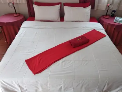 a red napkin on a white bed with two tables at The Clifton Room's in Centurion