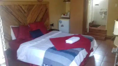 a bedroom with a bed with a red blanket on it at The Clifton Room's in Centurion