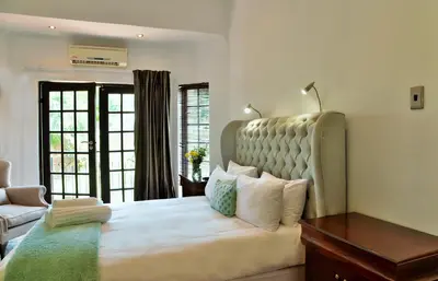 a bedroom with a large bed with a large headboard at Indlovukazi Guesthouse in Hartbeespoort