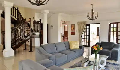 a living room with a blue couch and a staircase at Indlovukazi Guesthouse in Hartbeespoort