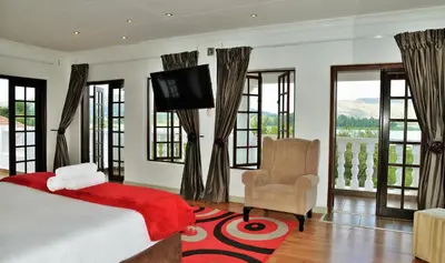 a bedroom with a bed and a television and a chair at Indlovukazi Guesthouse in Hartbeespoort