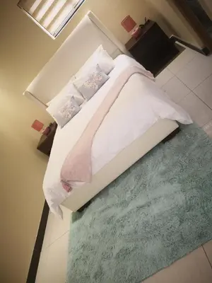 a bedroom with a white bed with a green rug at Mmakgabo Boutique Lodge in Bela-Bela