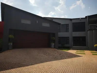 a building with a garage with a brick driveway at Mmakgabo Boutique Lodge in Bela-Bela