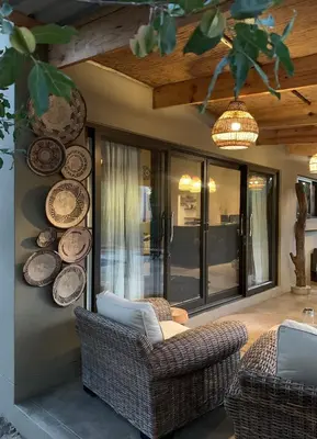 a living room with chairs and plates on the wall at Rooibos Luxury Bush Cottage in Hoedspruit