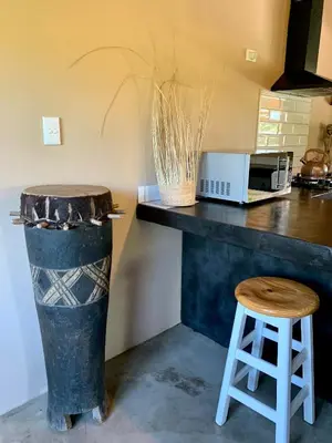 a kitchen with a counter with a stool and a microwave at Rooibos Luxury Bush Cottage in Hoedspruit