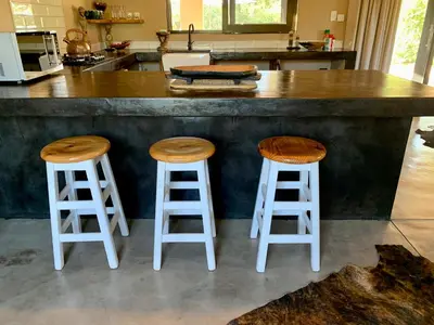 a kitchen with two stools at a kitchen counter at Rooibos Luxury Bush Cottage in Hoedspruit