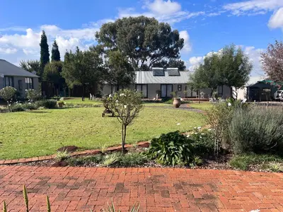 a garden with a house in the background with a tree at Three Thymes Inn in Tierpoort