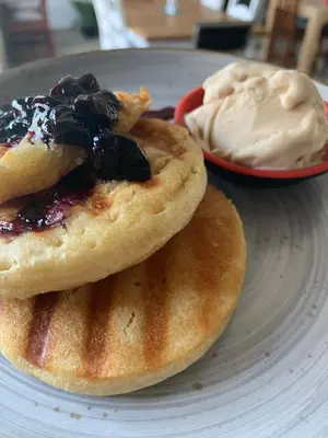 two pancakes with blueberries and whipped cream on a plate at Three Thymes Inn in Tierpoort