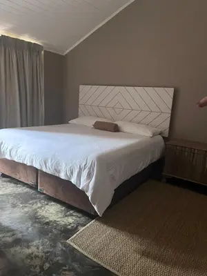 a bedroom with a large bed with white sheets at Three Thymes Inn in Tierpoort
