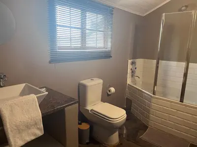 a bathroom with a toilet and a shower and a sink at Three Thymes Inn in Tierpoort