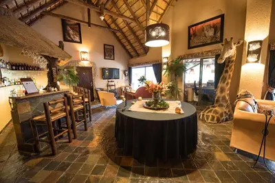 a restaurant with a table in a room with giraffes at African Rock Lodge in Hoedspruit