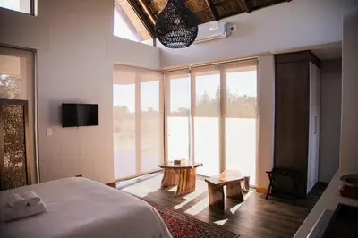 a bedroom with a bed and a large window at Kuwisa Lodge in Bela-Bela