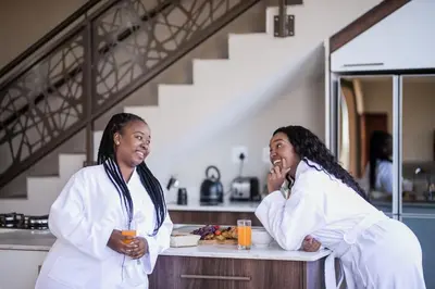 two women in a kitchen talking on their cell phones at Kuwisa Lodge in Bela-Bela